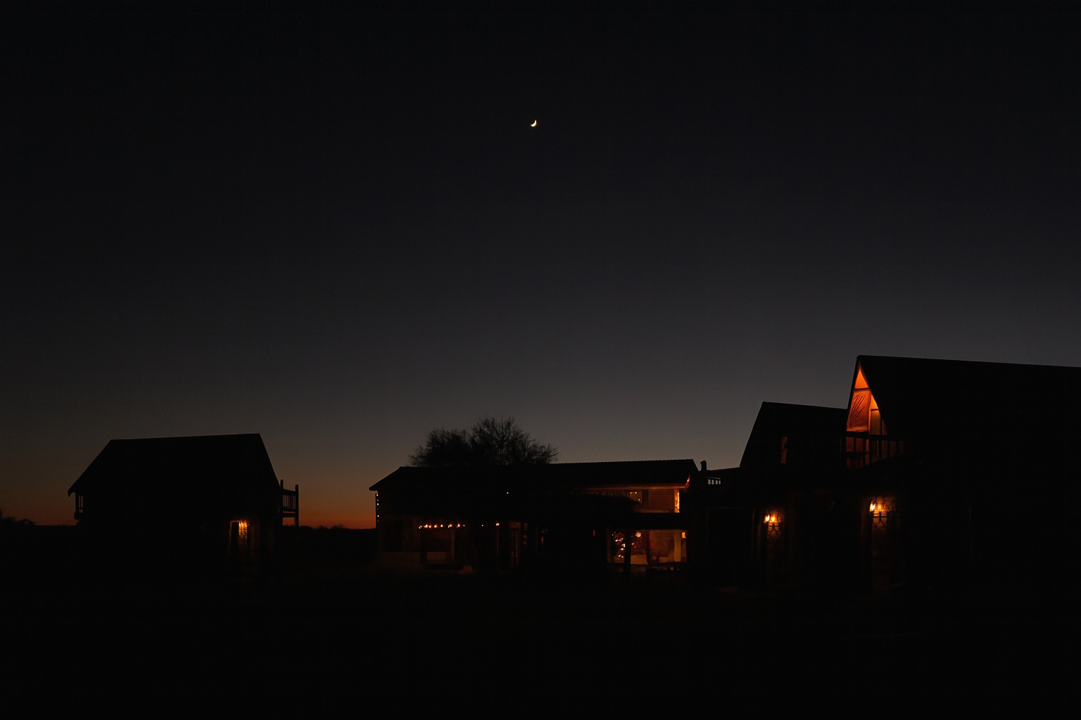 Night view of the illuminated Las Lajas Ranch base camp under a dark sky